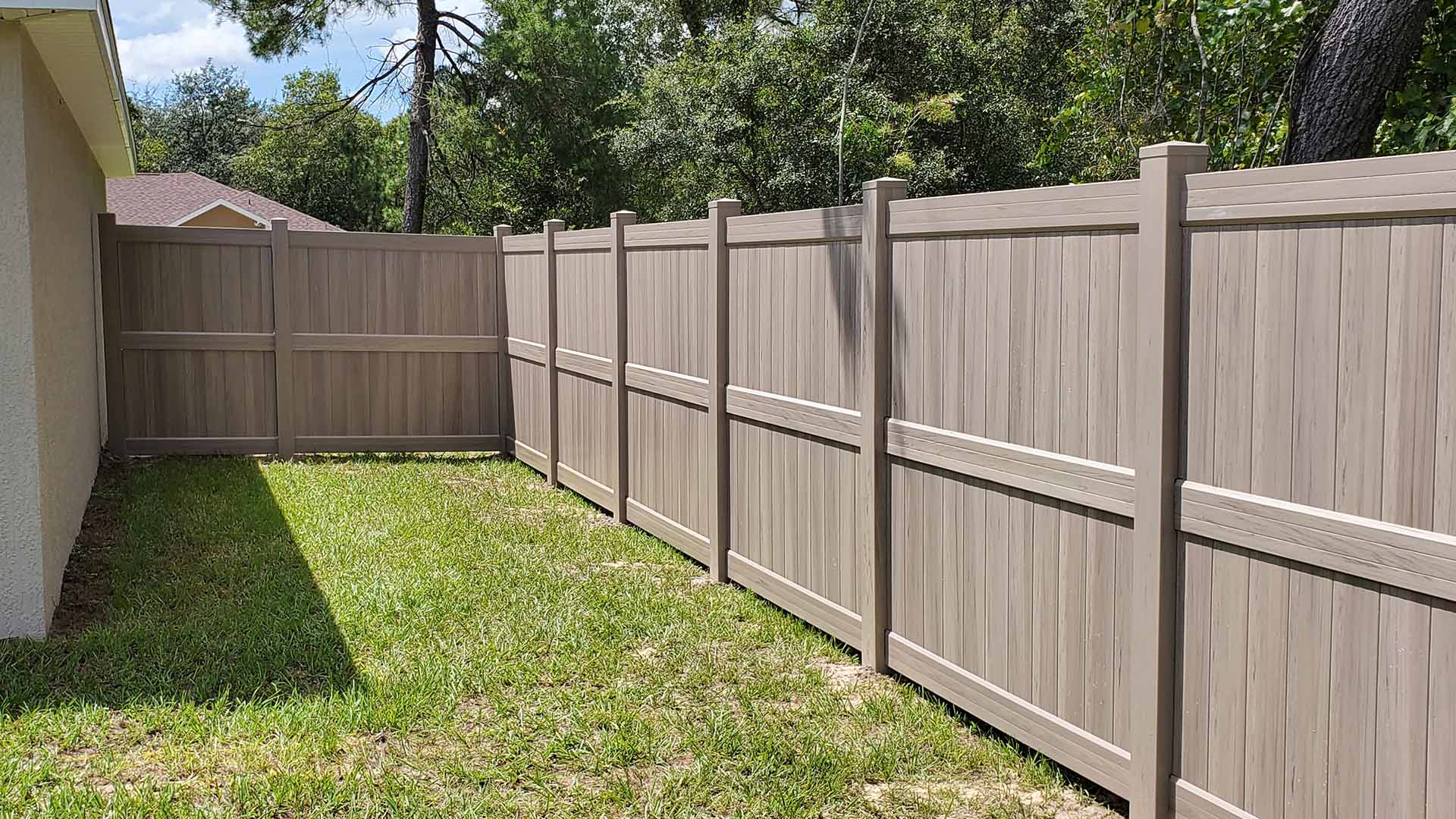 Tan vinyl privacy fence installed in a residential backyard in Central Florida