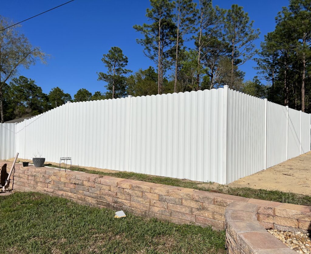 White Dura Fence that moves with the landscape, climbing up a retaining wall but maintaining it's shape